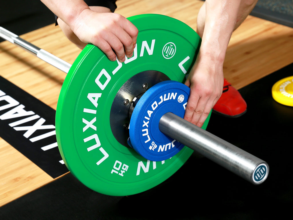 Close-up of hands loading LUXIAOJUN Urethane Change Plates 25KG Set onto a barbell